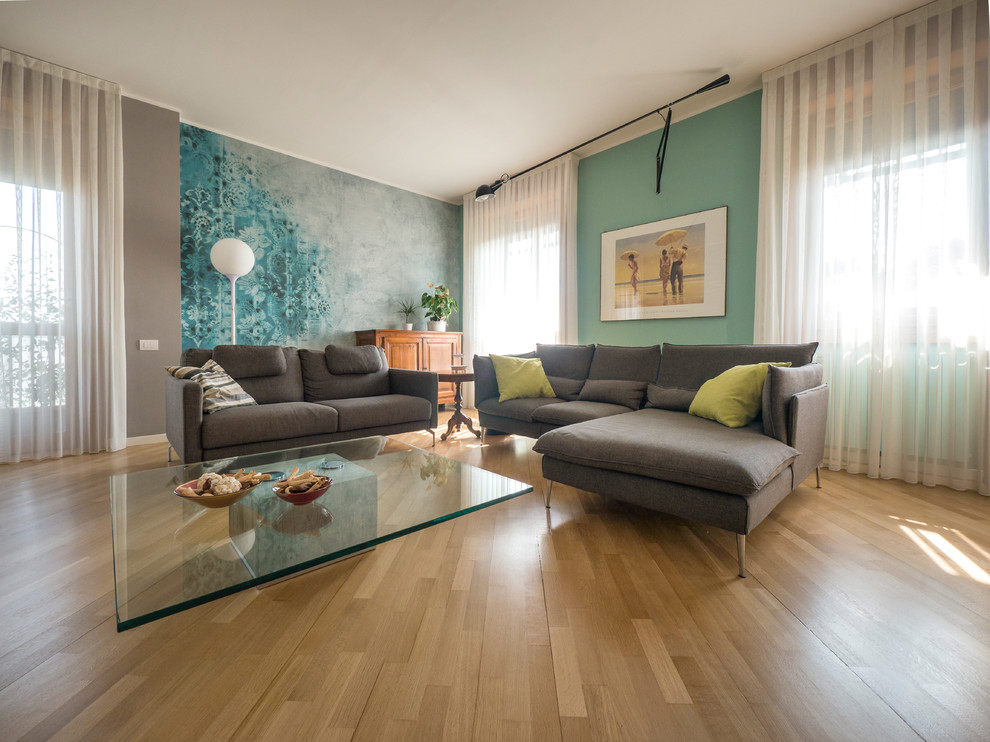 Design ideas for a large contemporary formal open concept living room in Milan with green walls, light hardwood floors and a freestanding tv.
