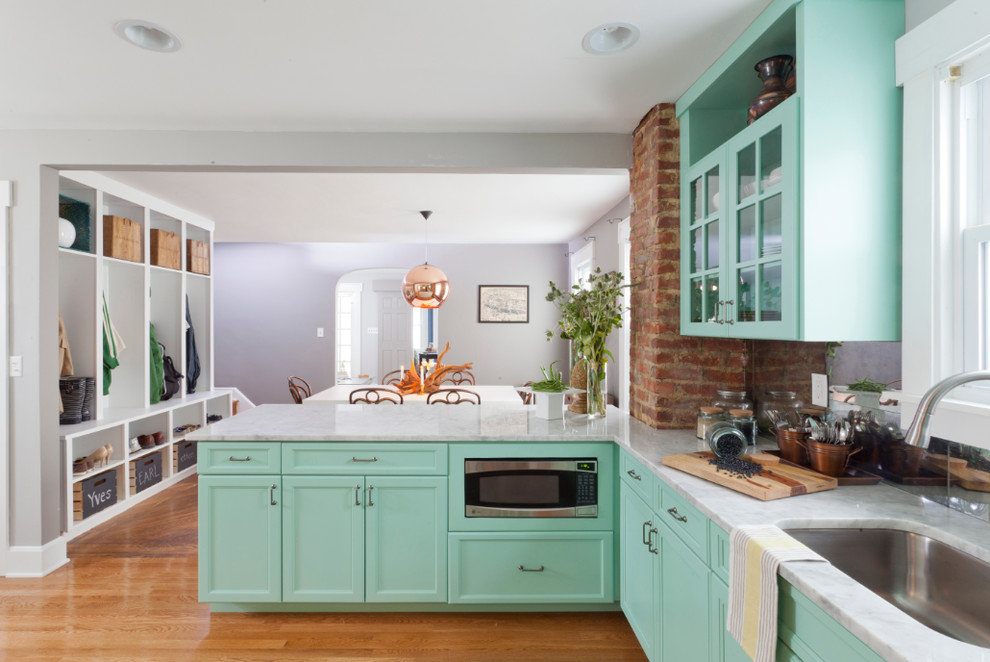 This is an example of a traditional u-shaped eat-in kitchen in New York with an undermount sink, blue cabinets, quartzite benchtops, mirror splashback, stainless steel appliances and shaker cabinets.