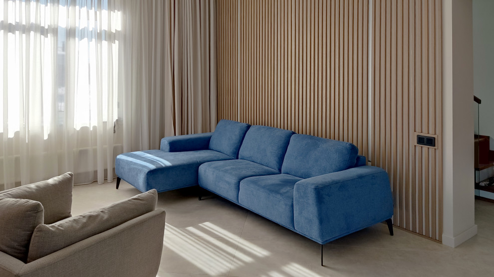 На фото: гостиная комната в стиле модернизм с бежевыми стенами, бежевым полом и синим диваном с