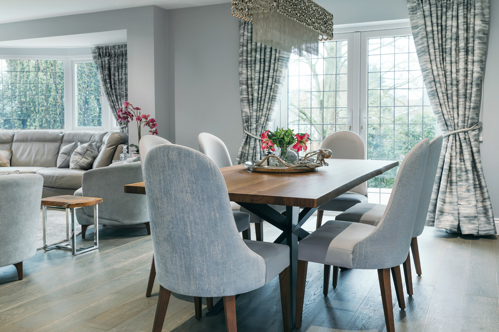 Photo of a mid-sized contemporary open plan dining in Essex with grey walls, vinyl floors, a wood stove, a wood fireplace surround and brown floor.
