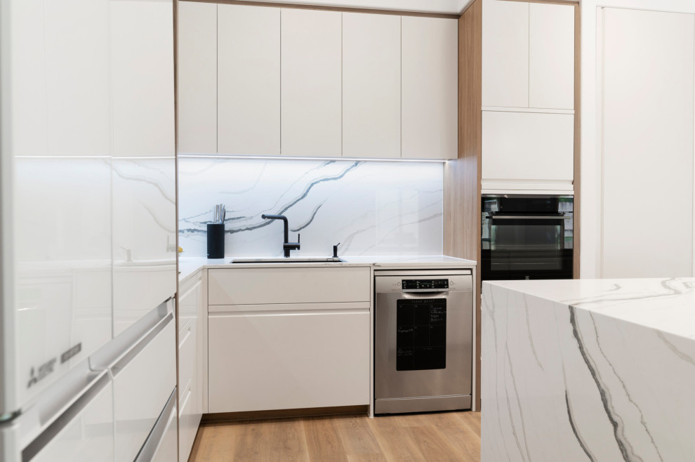 Design ideas for a large scandinavian open plan kitchen in Gold Coast - Tweed with a drop-in sink, white cabinets, quartz benchtops, white splashback, engineered quartz splashback, vinyl floors, with island, brown floor and white benchtop.