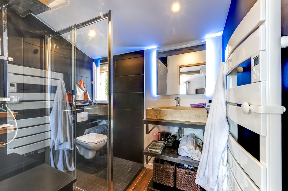 Photo of a small contemporary 3/4 bathroom in Other with open cabinets, black cabinets, a curbless shower, a wall-mount toilet, black tile, ceramic tile, black walls, mosaic tile floors, a drop-in sink, terrazzo benchtops, black floor and a sliding shower screen.