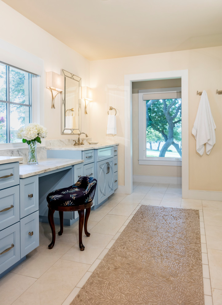 Cette image montre une grande salle de bain principale traditionnelle avec un placard à porte affleurante, des portes de placard bleues, une baignoire encastrée, une douche d'angle, un carrelage jaune, du carrelage en pierre calcaire, un mur blanc, un sol en calcaire, un lavabo encastré, un plan de toilette en quartz, un sol beige, une cabine de douche à porte battante, un plan de toilette multicolore, un banc de douche, meuble double vasque et meuble-lavabo encastré.