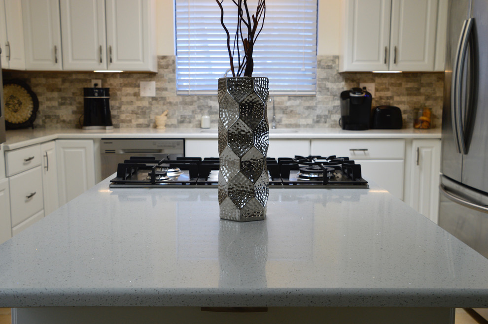 Inspiration for a mid-sized transitional l-shaped porcelain tile enclosed kitchen remodel in Albuquerque with an undermount sink, raised-panel cabinets, white cabinets, quartz countertops, beige backsplash, porcelain backsplash, stainless steel appliances and no island