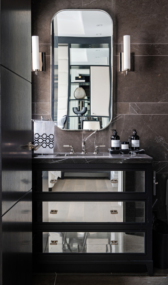 Immagine di un bagno di servizio chic con ante di vetro, ante nere, piastrelle marroni, piastrelle di marmo, pareti marroni, lavabo sottopiano, top in marmo, top nero e mobile bagno incassato