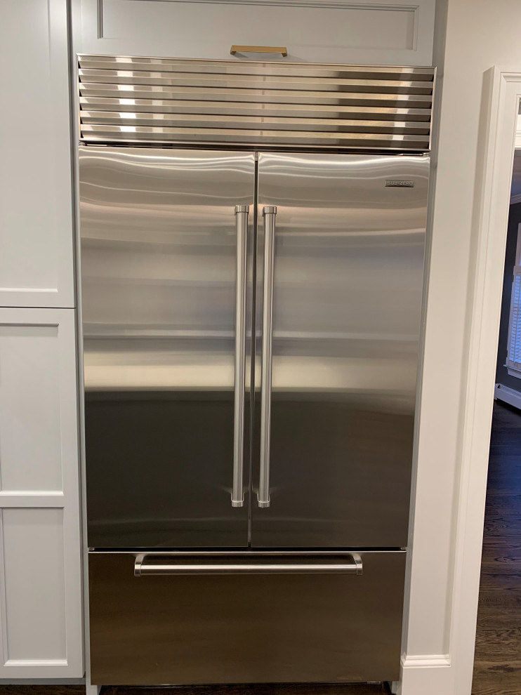 Enclosed kitchen - large transitional galley dark wood floor and brown floor enclosed kitchen idea in Boston with a farmhouse sink, raised-panel cabinets, gray cabinets, quartzite countertops, white backsplash, stone slab backsplash, stainless steel appliances, an island and white countertops