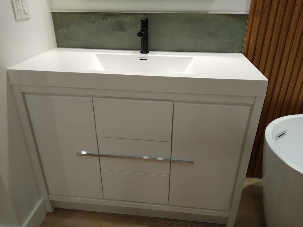 Inspiration for a mid-sized modern master vinyl floor, beige floor and single-sink bathroom remodel in Toronto with flat-panel cabinets, white cabinets, a one-piece toilet, white walls, an integrated sink, onyx countertops, a hinged shower door, white countertops and a freestanding vanity