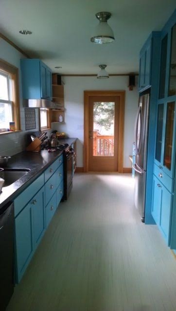 Design ideas for a mid-sized transitional galley separate kitchen in Seattle with an undermount sink, shaker cabinets, blue cabinets, solid surface benchtops, stainless steel appliances, light hardwood floors and beige floor.