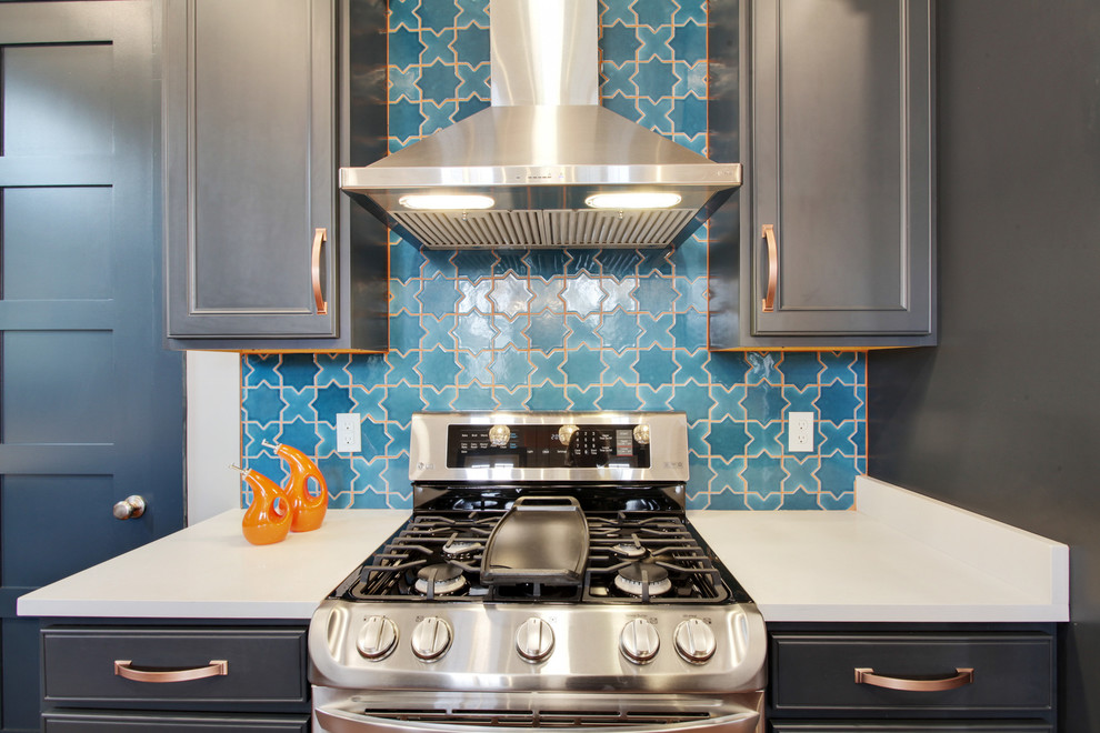This is an example of a large eclectic l-shaped eat-in kitchen in New Orleans with an undermount sink, flat-panel cabinets, blue cabinets, quartz benchtops, blue splashback, ceramic splashback, stainless steel appliances, medium hardwood floors, with island, brown floor and white benchtop.