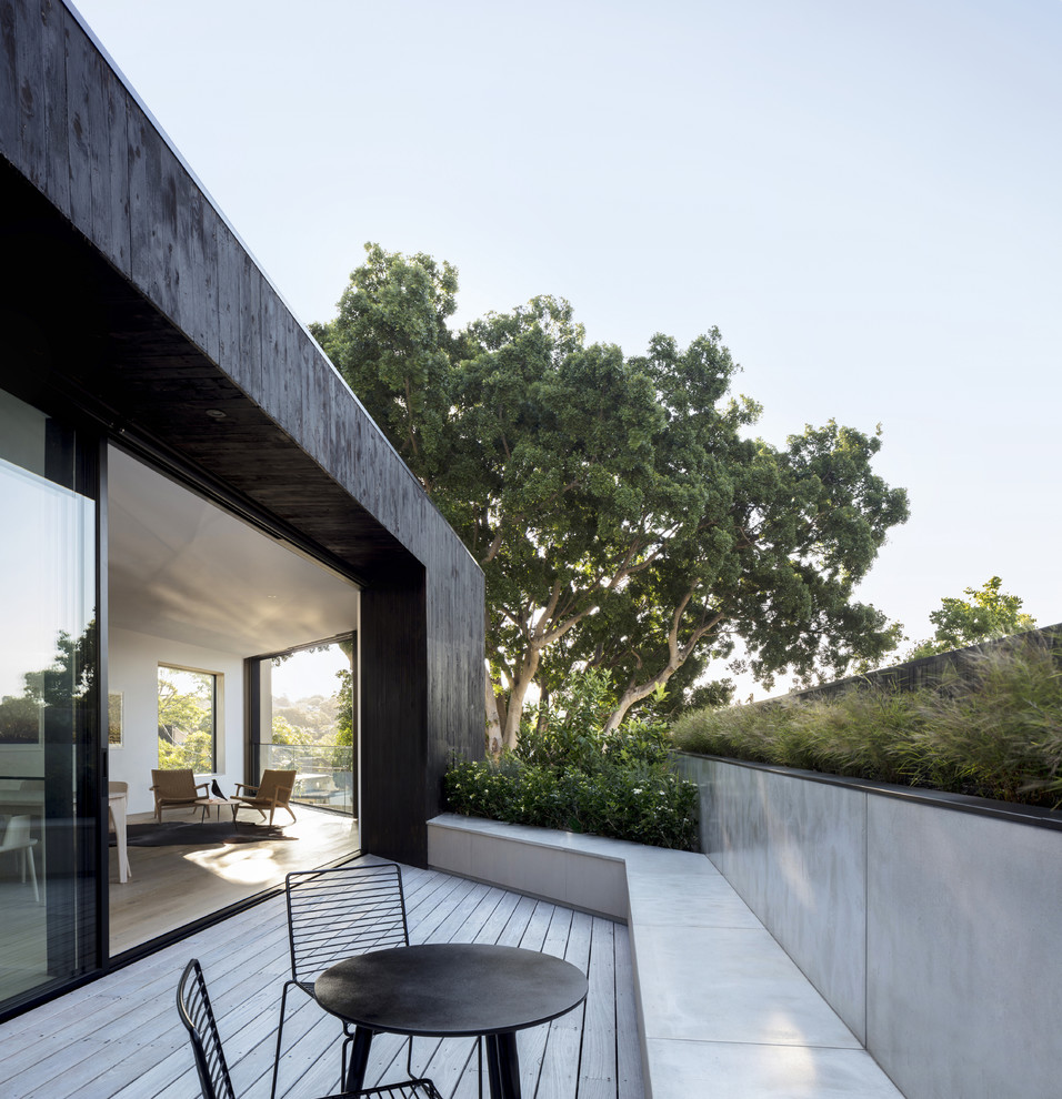 Design ideas for a mid-sized modern first floor deck in Sydney with a container garden and a roof extension.