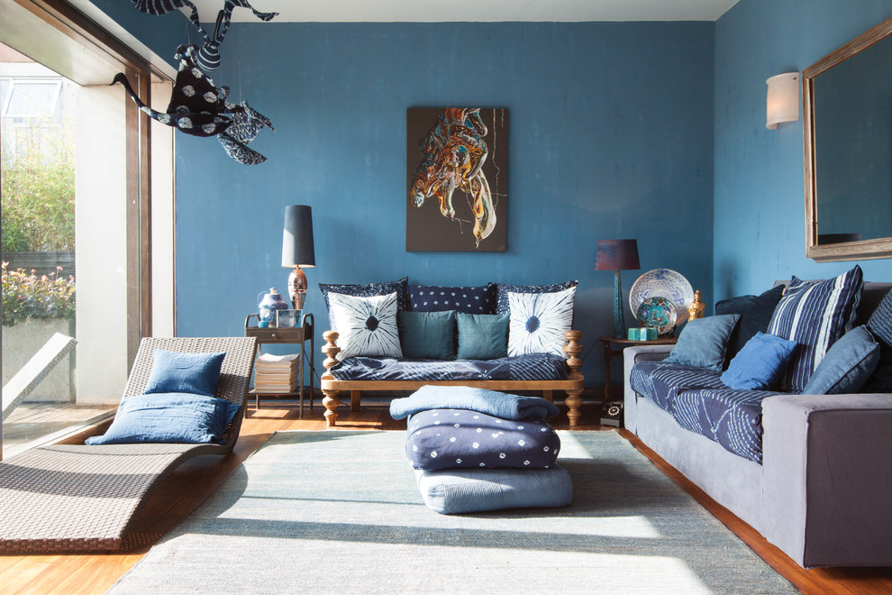Mid-sized eclectic formal open concept living room in London with blue walls and medium hardwood floors.