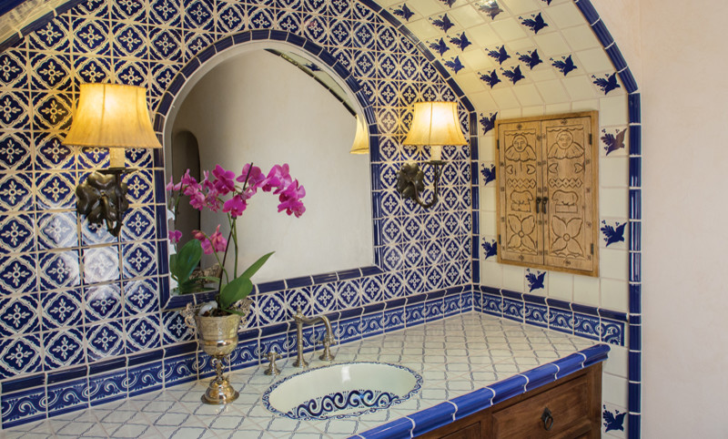 Large mediterranean master bathroom in Albuquerque with a drop-in sink, raised-panel cabinets, dark wood cabinets, tile benchtops, a corner shower, blue tile, terra-cotta tile, beige walls and medium hardwood floors.