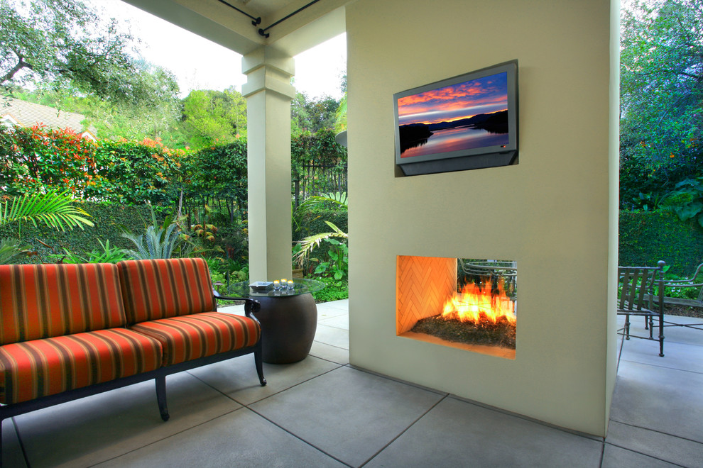 Small tropical backyard patio in Los Angeles with a fire feature, a roof extension and concrete slab.