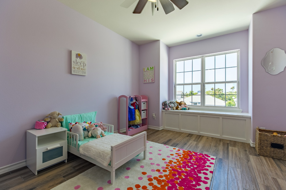 Design ideas for a mid-sized beach style kids' room for girls in Austin with purple walls and medium hardwood floors.