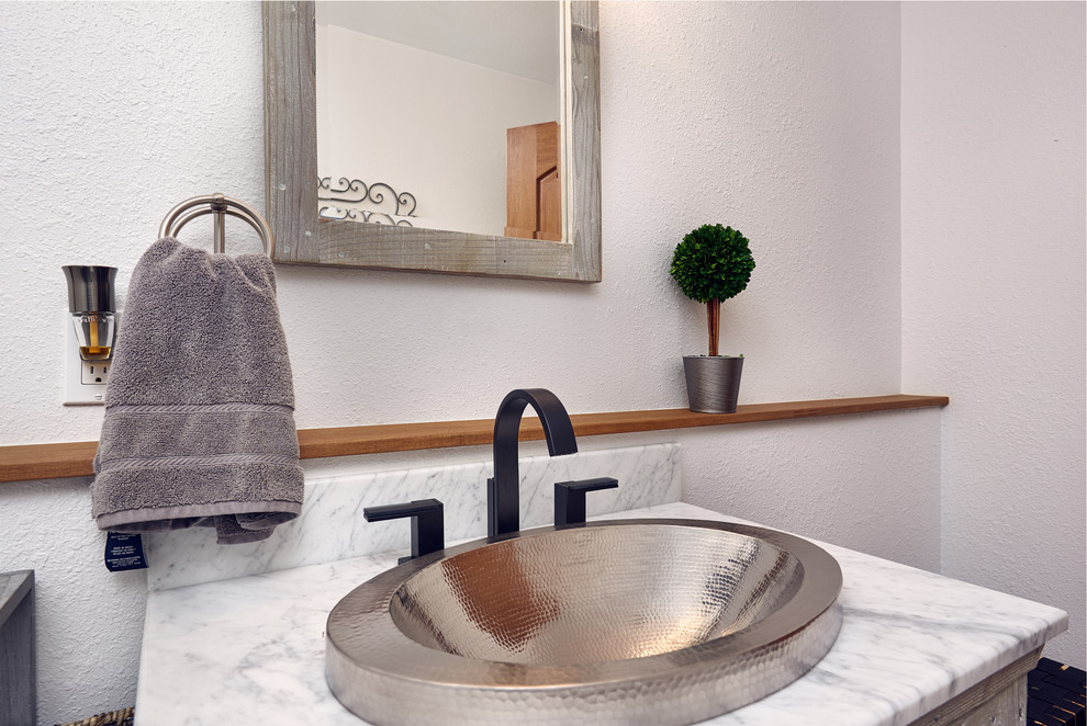 This is an example of a mid-sized transitional powder room in Other with flat-panel cabinets, light wood cabinets, a two-piece toilet, white walls, pebble tile floors, a drop-in sink, marble benchtops, multi-coloured floor and grey benchtops.