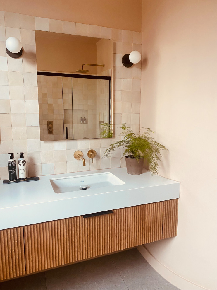 Inredning av ett modernt stort vit vitt en-suite badrum, med luckor med profilerade fronter, skåp i mörkt trä, våtrum, en vägghängd toalettstol, rosa kakel, rosa väggar, klinkergolv i porslin, ett väggmonterat handfat, grått golv och dusch med skjutdörr