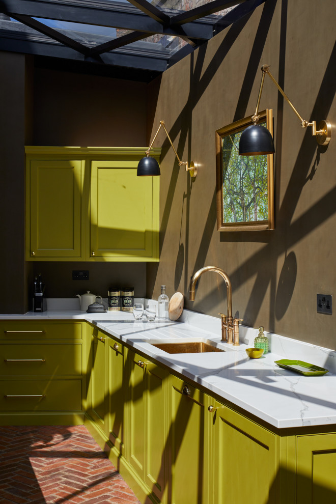 This is an example of a large modern l-shaped eat-in kitchen in London with a drop-in sink, shaker cabinets, green cabinets, quartzite benchtops, green splashback, brick splashback, panelled appliances, brick floors, with island, brown floor and white benchtop.