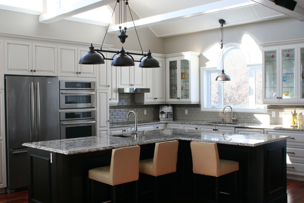 Inspiration for a huge transitional l-shaped medium tone wood floor and brown floor open concept kitchen remodel in Montreal with an undermount sink, glass-front cabinets, white cabinets, granite countertops, gray backsplash, ceramic backsplash, stainless steel appliances, an island and multicolored countertops