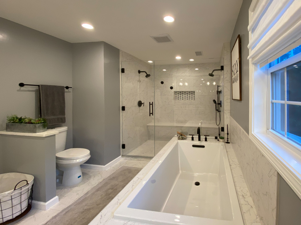 This is an example of an expansive master bathroom in Bridgeport with shaker cabinets, white cabinets, a drop-in tub, a double shower, a two-piece toilet, white tile, porcelain tile, grey walls, porcelain floors, an undermount sink, engineered quartz benchtops, a hinged shower door, white benchtops, a double vanity and a freestanding vanity.