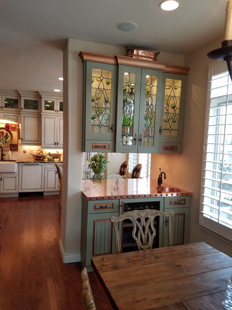 Inspiration for a mid-sized country single-wall wet bar in Denver with raised-panel cabinets, green cabinets, copper benchtops, medium hardwood floors and brown floor.