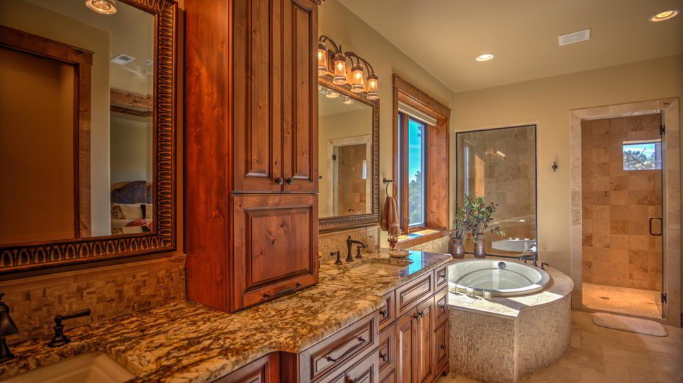 Photo of a large traditional master bathroom in Denver with raised-panel cabinets, brown cabinets, a drop-in tub, a double shower, beige tile, beige walls, ceramic floors, a drop-in sink and granite benchtops.