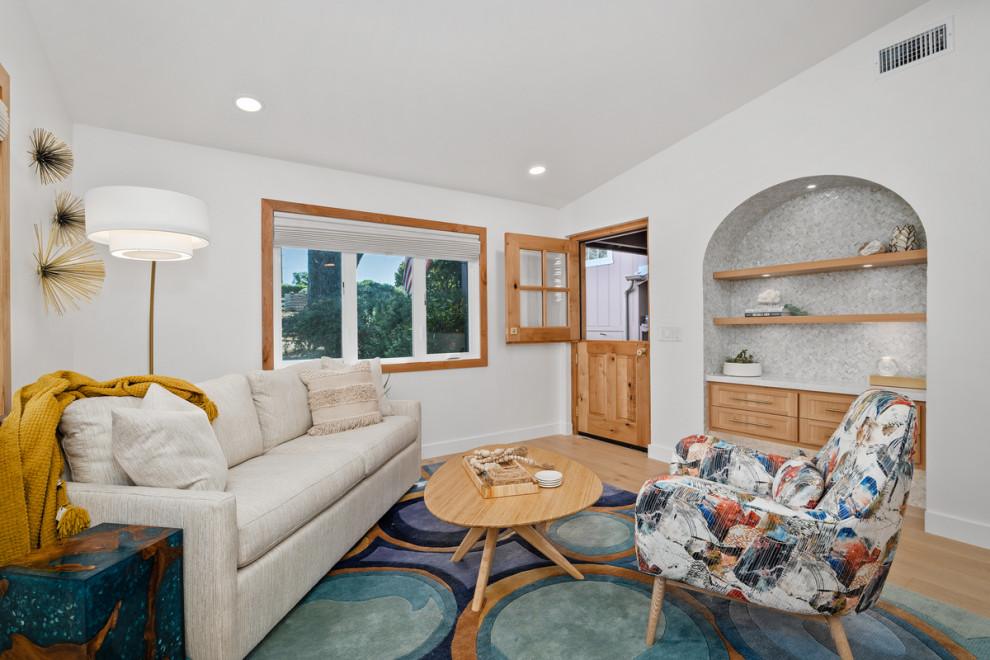 This is an example of a medium sized coastal open plan living room in San Diego with a music area, white walls, light hardwood flooring and a vaulted ceiling.