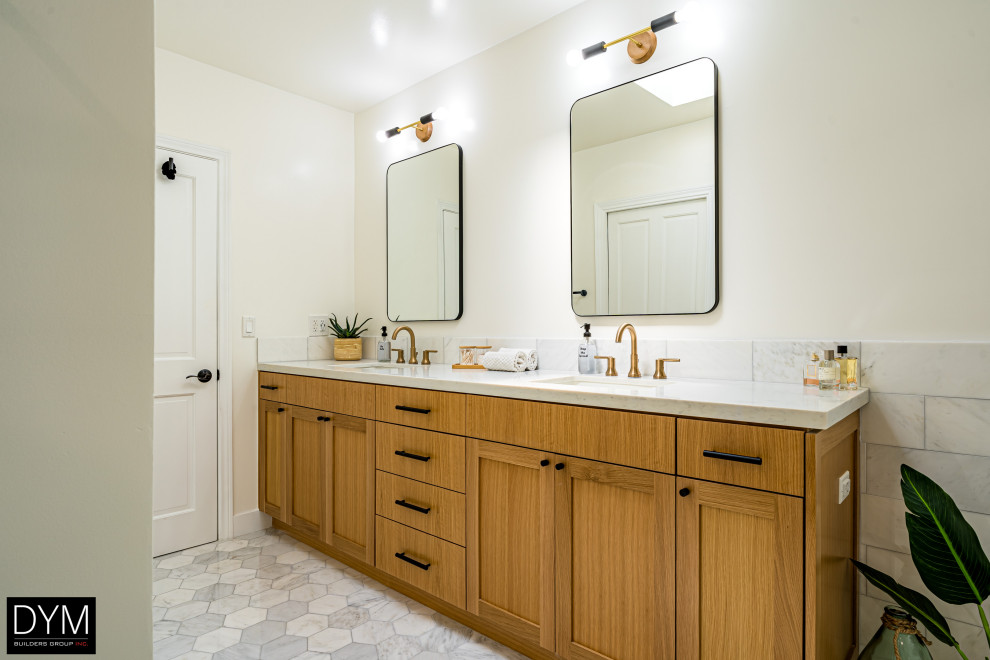 Photo of a large midcentury master bathroom in Los Angeles with shaker cabinets, medium wood cabinets, a freestanding tub, a corner shower, a one-piece toilet, white tile, cement tile, white walls, porcelain floors, a drop-in sink, marble benchtops, grey floor, a sliding shower screen, white benchtops, a shower seat, a double vanity, a built-in vanity, wallpaper and wallpaper.