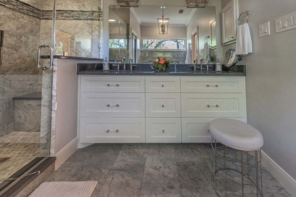 Mid-sized transitional master wet room bathroom in Houston with shaker cabinets, white cabinets, a freestanding tub, a two-piece toilet, gray tile, marble, grey walls, marble floors, an undermount sink, quartzite benchtops, grey floor, a hinged shower door and black benchtops.