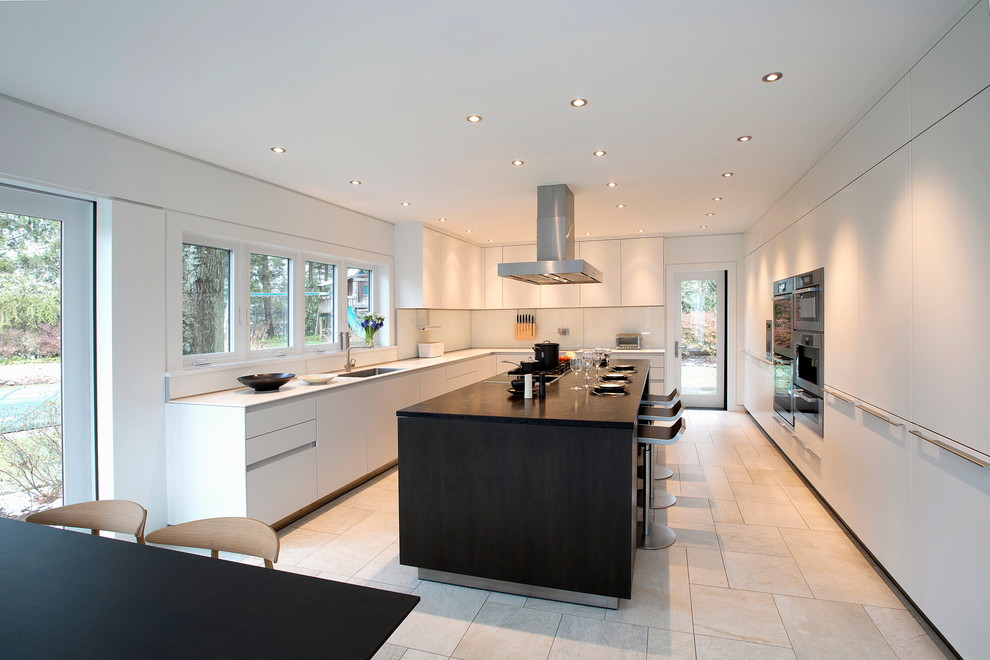 Inspiration for a large contemporary l-shaped eat-in kitchen in New York with a single-bowl sink, flat-panel cabinets, white cabinets, marble benchtops, white splashback, glass sheet splashback, stainless steel appliances, ceramic floors and with island.