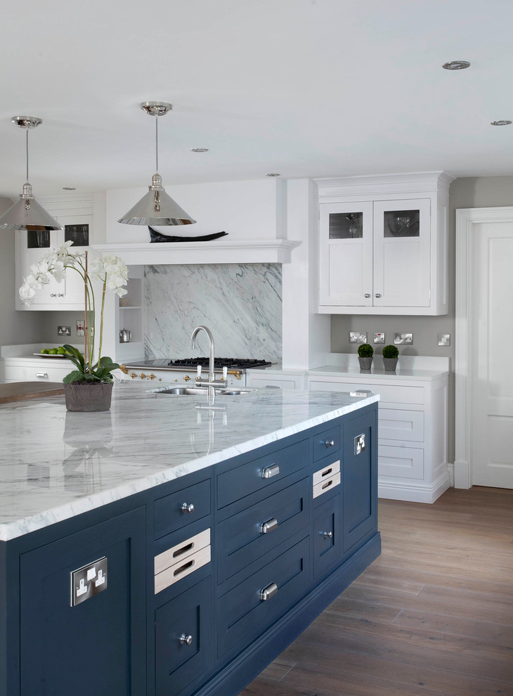 Large transitional u-shaped open plan kitchen in Dublin with shaker cabinets, white cabinets, marble benchtops, grey splashback, marble splashback, white appliances, medium hardwood floors, with island, brown floor and grey benchtop.