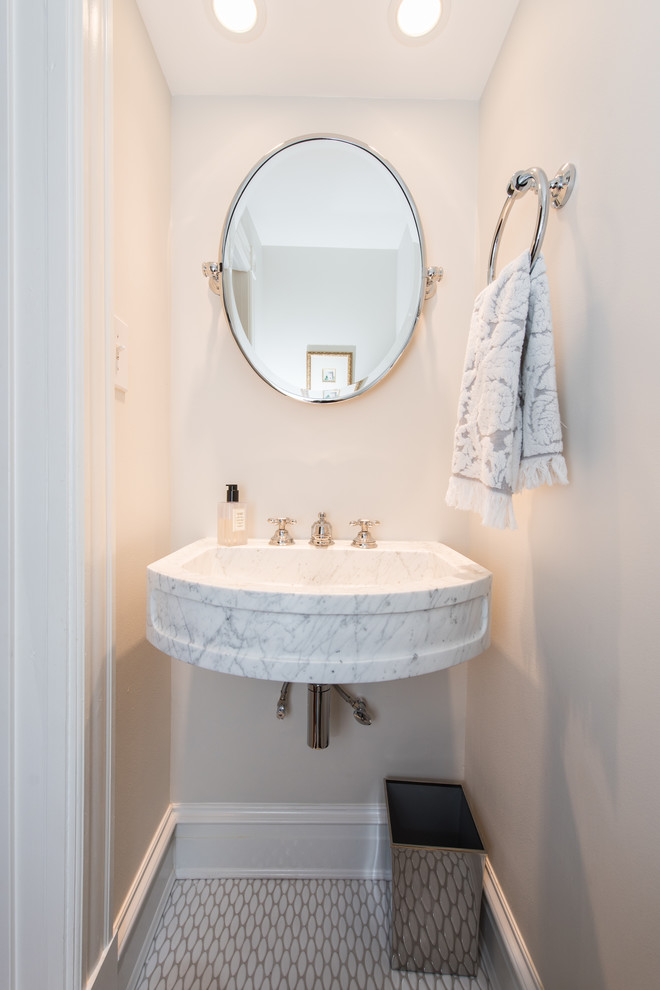 This is an example of a small traditional powder room in DC Metro with beige tile, beige walls, porcelain floors, marble benchtops, a wall-mount sink and white floor.