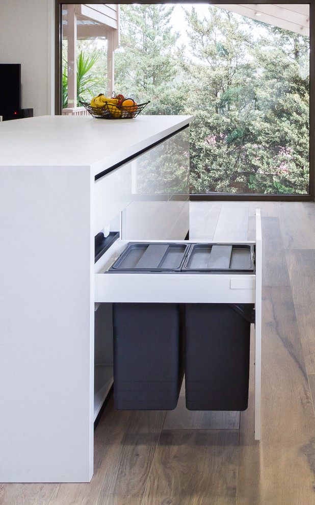 Expansive modern u-shaped eat-in kitchen in Melbourne with a double-bowl sink, flat-panel cabinets, black cabinets, quartz benchtops, white splashback, window splashback, stainless steel appliances, porcelain floors, with island, brown floor and white benchtop.