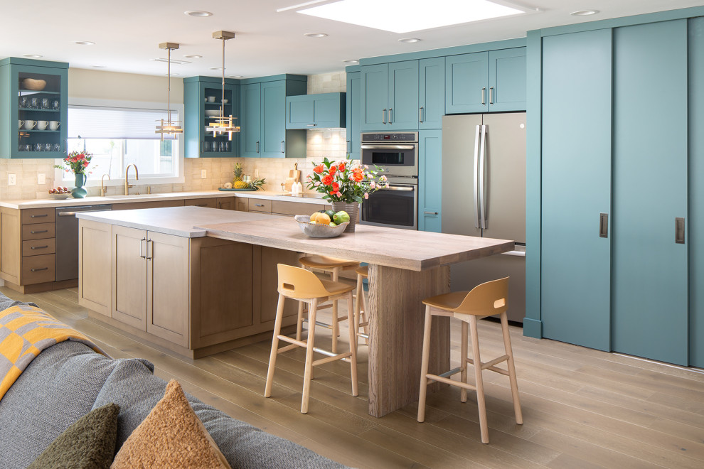 Inspiration for a large contemporary l-shaped eat-in kitchen in San Diego with a double-bowl sink, shaker cabinets, blue cabinets, quartz benchtops, beige splashback, limestone splashback, stainless steel appliances, vinyl floors, with island, beige floor and beige benchtop.