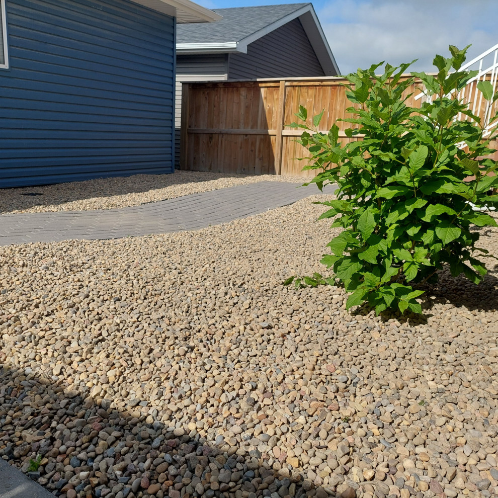 Design ideas for a small and desert look traditional backyard full sun xeriscape in Calgary with gravel.