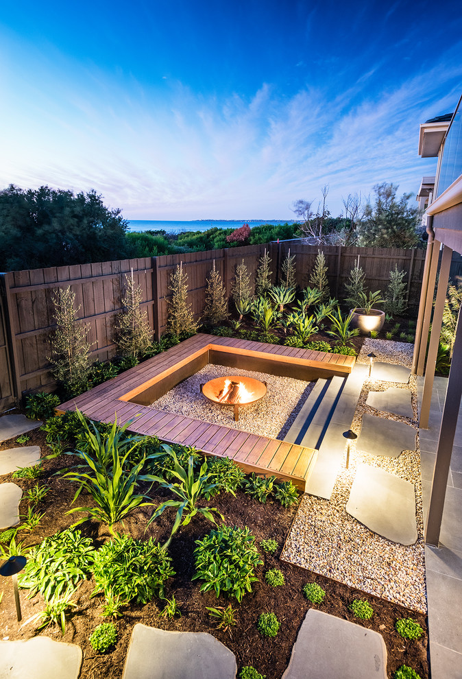 Mid-sized beach style backyard full sun garden in Melbourne with a fire feature and gravel for winter.