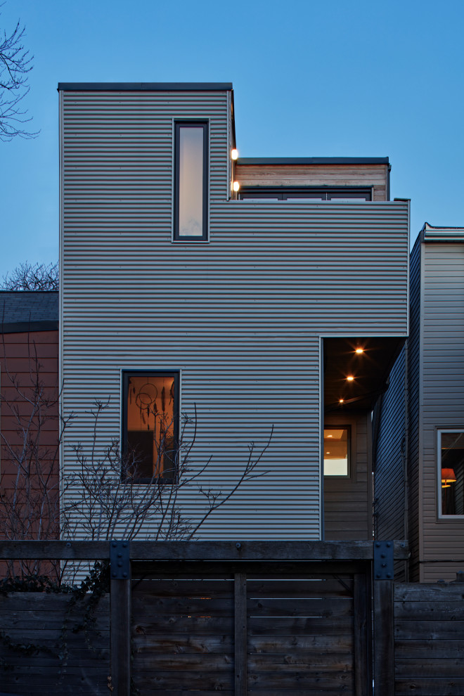 Photo of a small scandinavian three-storey townhouse exterior in Toronto with metal siding and a flat roof.