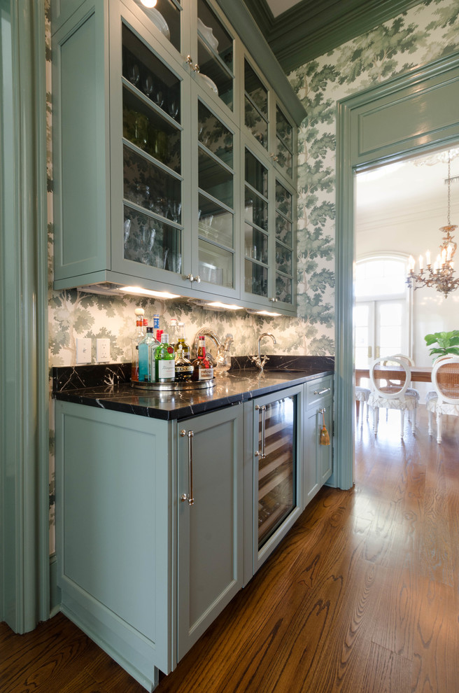 Design ideas for a mid-sized traditional single-wall wet bar in New Orleans with an undermount sink, raised-panel cabinets, green cabinets, marble benchtops, black splashback and dark hardwood floors.