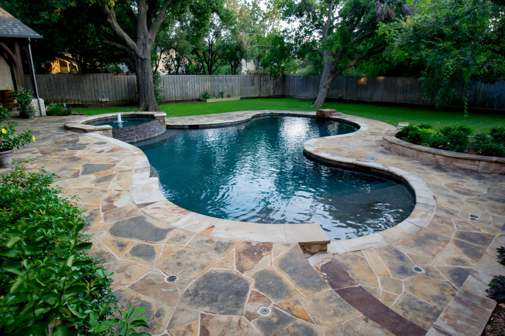 Mid-sized country backyard custom-shaped pool in Dallas with a water feature and natural stone pavers.