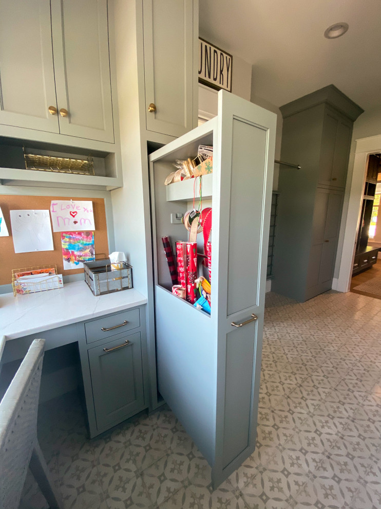 Réalisation d'une très grande buanderie tradition dédiée avec un évier de ferme, des portes de placard grises, un plan de travail en quartz modifié, une crédence en céramique, un mur blanc, un sol en carrelage de porcelaine et des machines côte à côte.