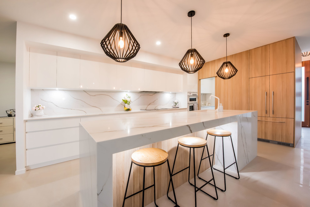 Inspiration for a large contemporary galley open plan kitchen in Other with an undermount sink, flat-panel cabinets, light wood cabinets, marble benchtops, white splashback, marble splashback, white appliances, ceramic floors, with island, white floor and white benchtop.
