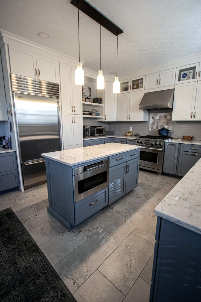 Inspiration for a mid-sized transitional u-shaped eat-in kitchen in Cleveland with an undermount sink, flat-panel cabinets, blue cabinets, quartz benchtops, grey splashback, ceramic splashback, stainless steel appliances, ceramic floors, with island, grey floor and grey benchtop.