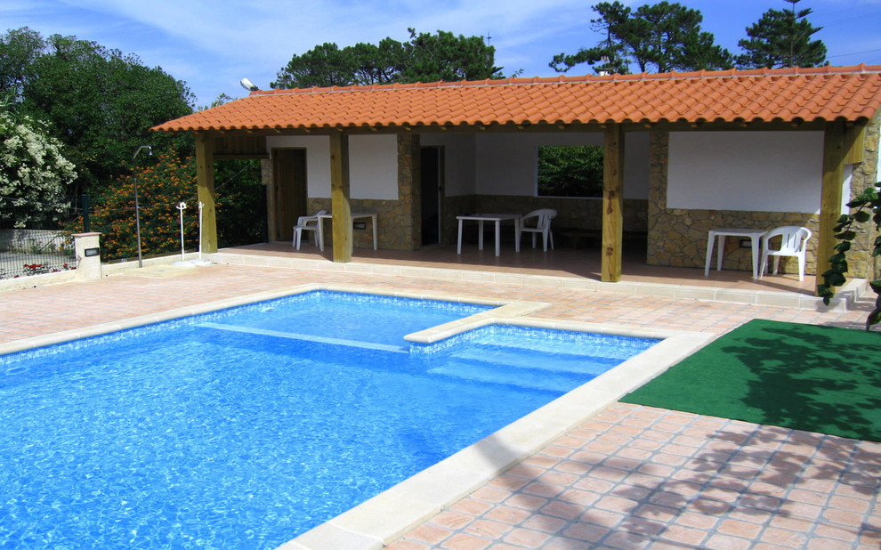 This is an example of a mid-sized country front yard rectangular lap pool in Barcelona with a pool house.