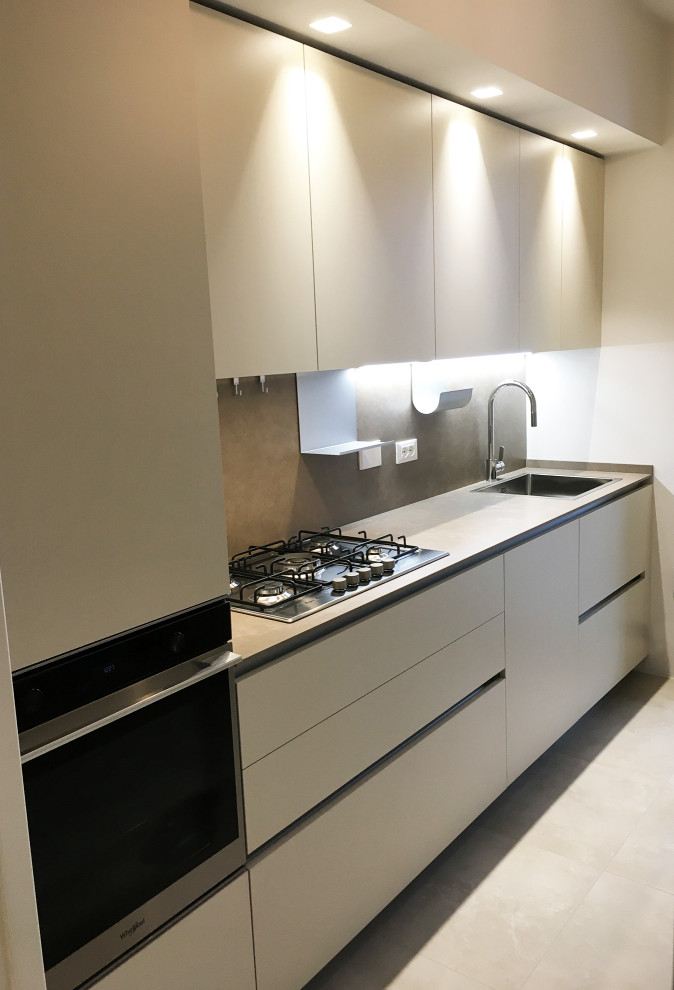 Photo of a small modern single-wall separate kitchen in Other with flat-panel cabinets, beige cabinets, tile benchtops, brown splashback, porcelain splashback, stainless steel appliances and brown benchtop.