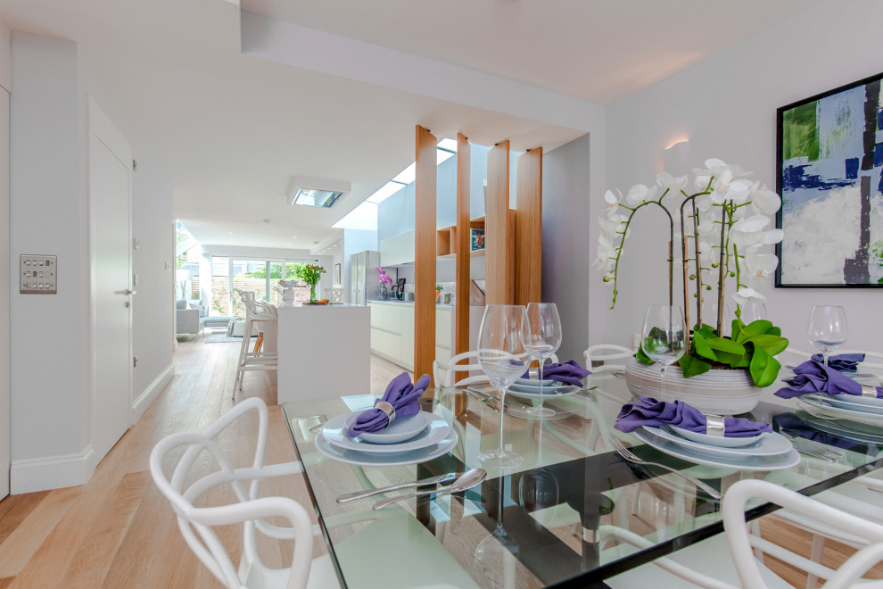 Photo of a mid-sized contemporary dining room in London with white walls, light hardwood floors and brown floor.