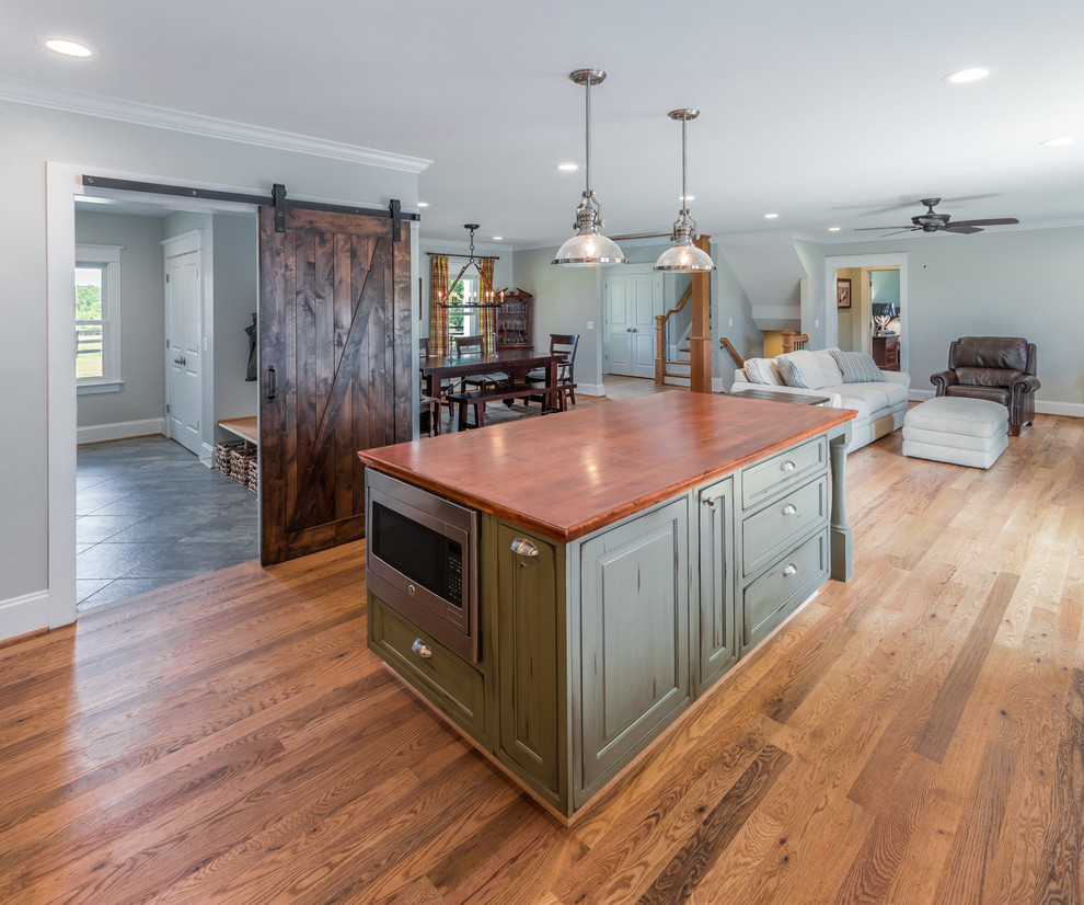 Photo of a country l-shaped kitchen in DC Metro with wood benchtops, light hardwood floors and with island.