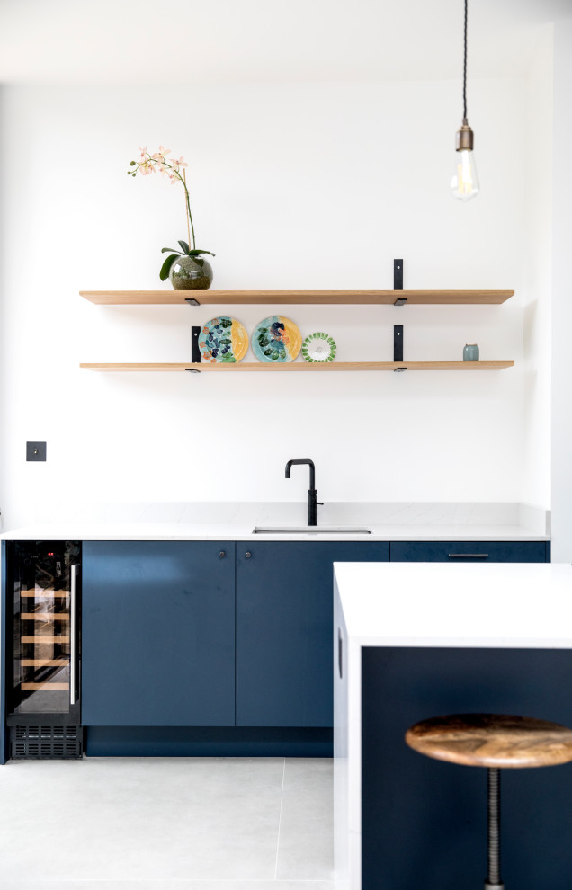 Design ideas for an expansive modern galley open plan kitchen in London with an integrated sink, flat-panel cabinets, blue cabinets, quartzite benchtops, cement tiles, with island, grey floor and white benchtop.