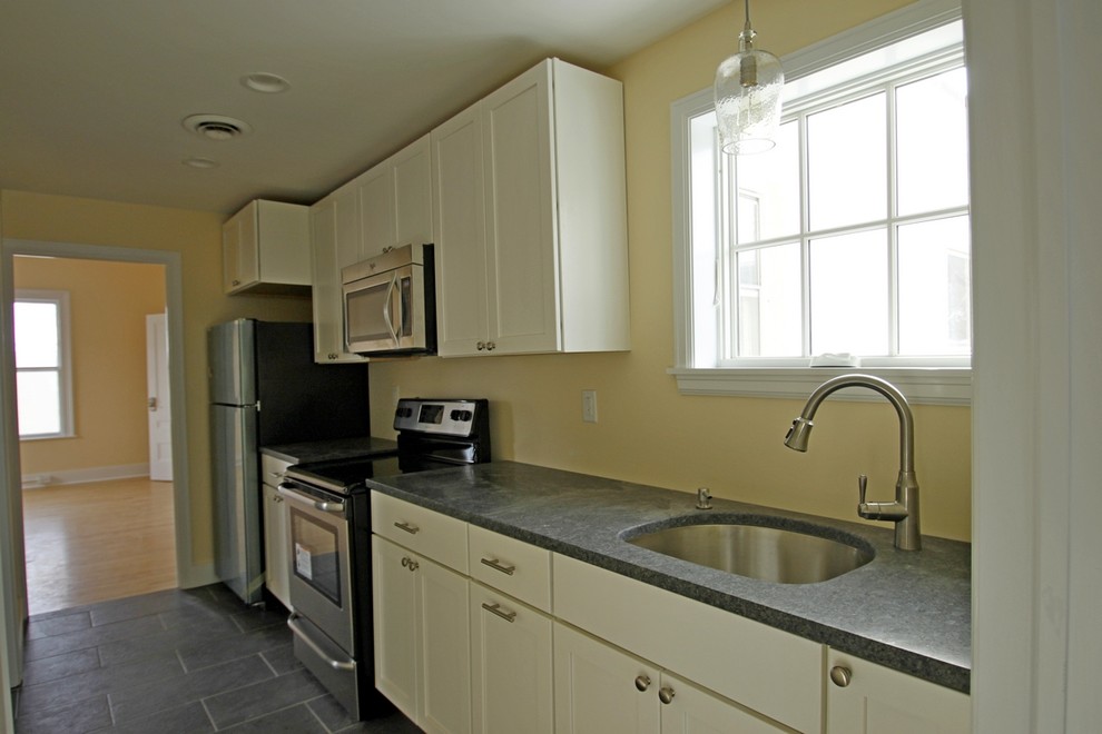 Kitchen - transitional single-wall slate floor kitchen idea in Burlington with an undermount sink, white cabinets, granite countertops, stainless steel appliances and no island