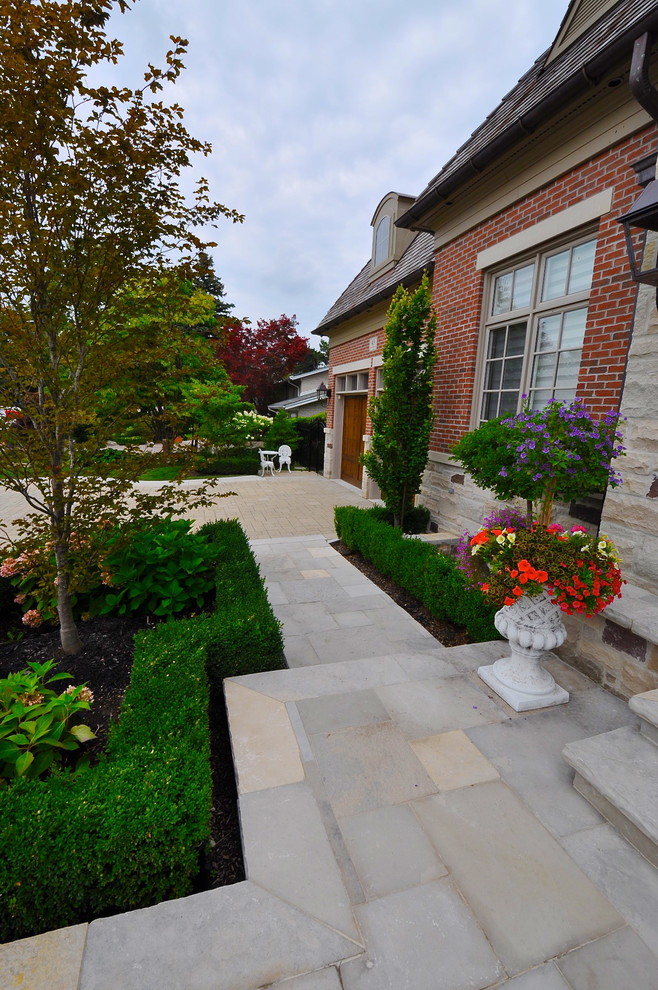 Design ideas for a large traditional front yard full sun formal garden in Toronto with natural stone pavers and a garden path.