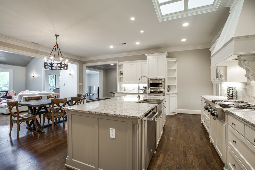 Inspiration for a large transitional u-shaped eat-in kitchen in Dallas with an undermount sink, recessed-panel cabinets, white cabinets, granite benchtops, beige splashback, ceramic splashback, stainless steel appliances, dark hardwood floors and with island.