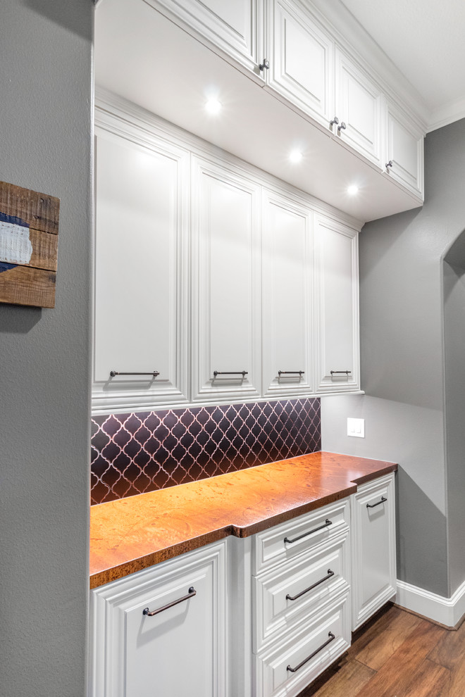 Inspiration for a large transitional u-shaped dark wood floor and brown floor kitchen pantry remodel in Houston with a farmhouse sink, raised-panel cabinets, gray cabinets, quartzite countertops, gray backsplash, limestone backsplash, stainless steel appliances, a peninsula and gray countertops